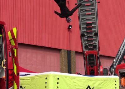 Fireman practising high-altitude rescue with safety cushion.