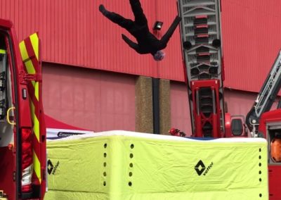 Firefighter safety drill: person falling onto inflatable cushion.