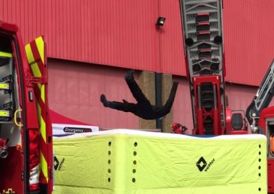 Firefighter using safety jump cushion during a rescue simulation.