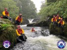 Rescue team members in river training with safety gear.