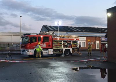 Fire truck at industrial site with firefighters.