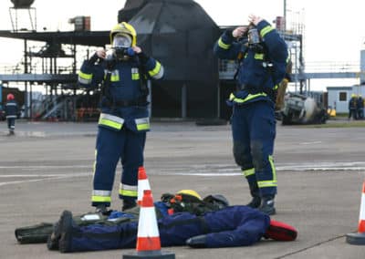 Firefighters in training place dummy between traffic cones.