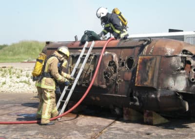 Firefighters training with damaged tanker and hoses.