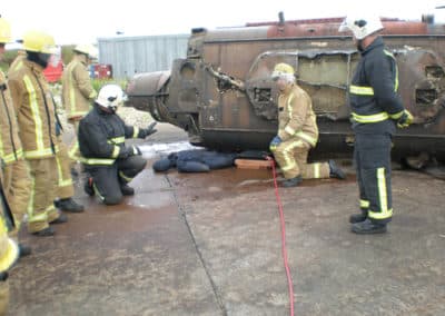 Firefighters performing rescue drill with overturned vehicle.
