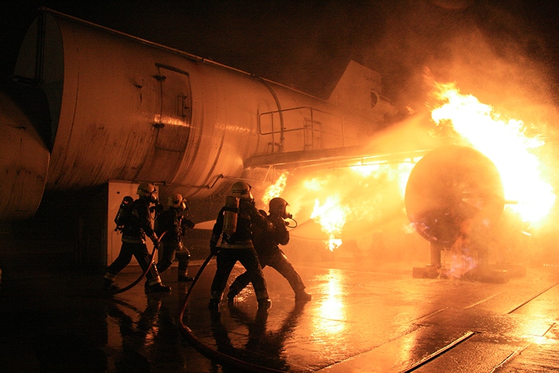 Firefighters battling aeroplane fire at night.