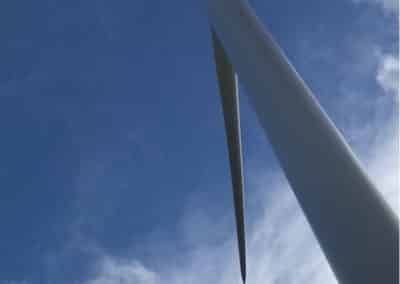 Worker abseiling down wind turbine for maintenance.