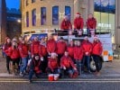 Christmas charity group in front of festive bus.