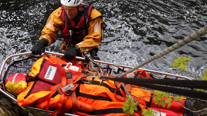 Rescue worker aiding injured person in river.