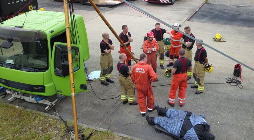 Firefighters in training exercise near green lorry.