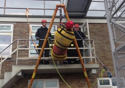 Firefighters conducting high-rise rescue training with mannequin.