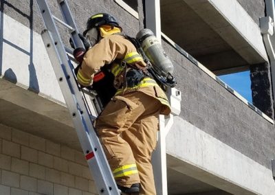 Firefighter climbing ladder during a building rescue mission.