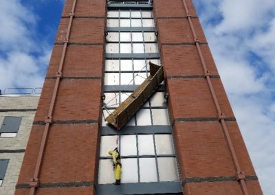 Person suspended on scaffold cleaning building windows.