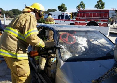 Firefighters using equipment in car rescue training session.