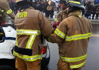 Firefighters rescuing person from car accident scene.