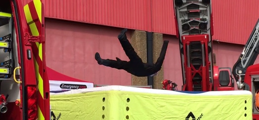 Firefighter jumps onto safety cushion during a drill.