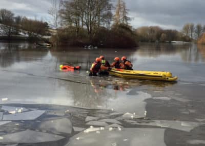 Rescue team saving person from icy water.