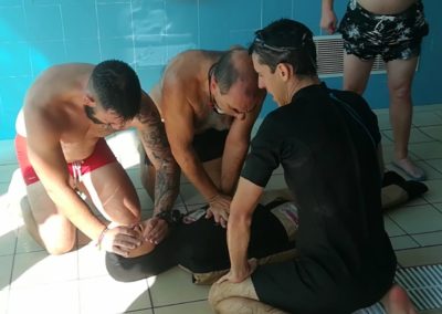 Lifeguards performing CPR training by a swimming pool.