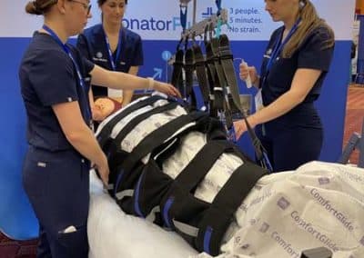 Healthcare professionals demonstrating patient lifting equipment.